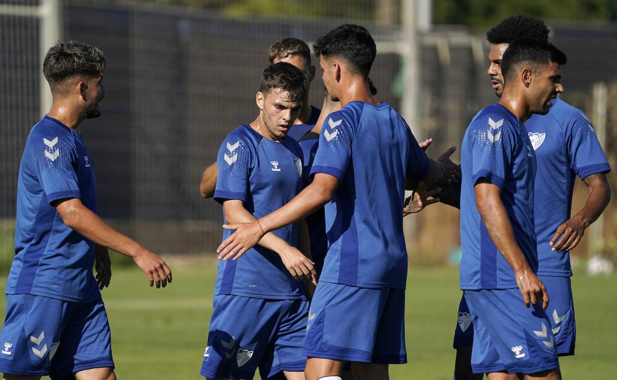 Jugadores del Málaga felicitan a Febas por su gol ayer contra el Vélez en un partido de entrenamiento.