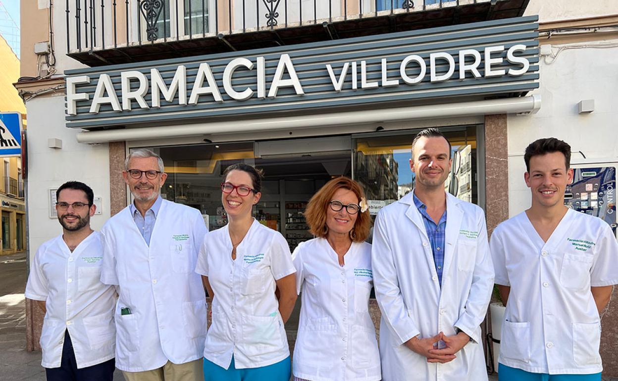 Tercera y cuarta generación con empleados ante la puerta de la farmacia. 