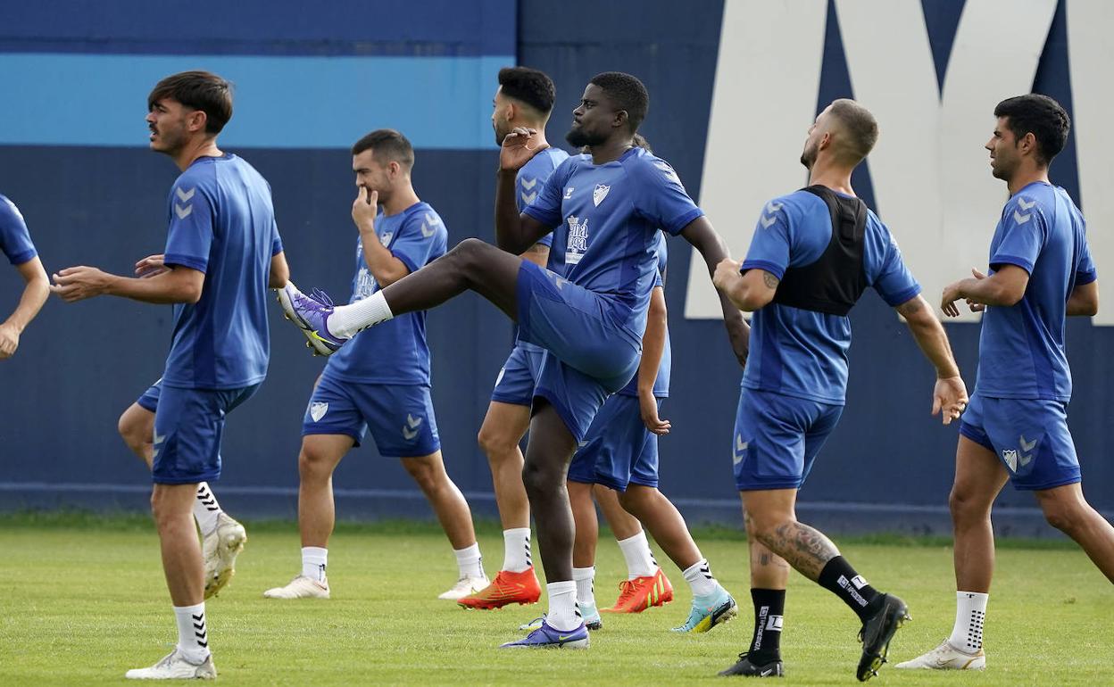 El jugador del Málaga, Alfred N'Diaye (en el centro), realiza ejercicios de calentamiento en un entrenamiento reciente.