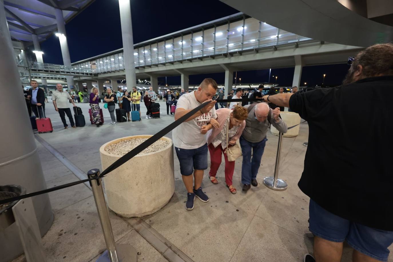 Un taxista ayuda a unas personas mayores en la cola del aeropuerto.