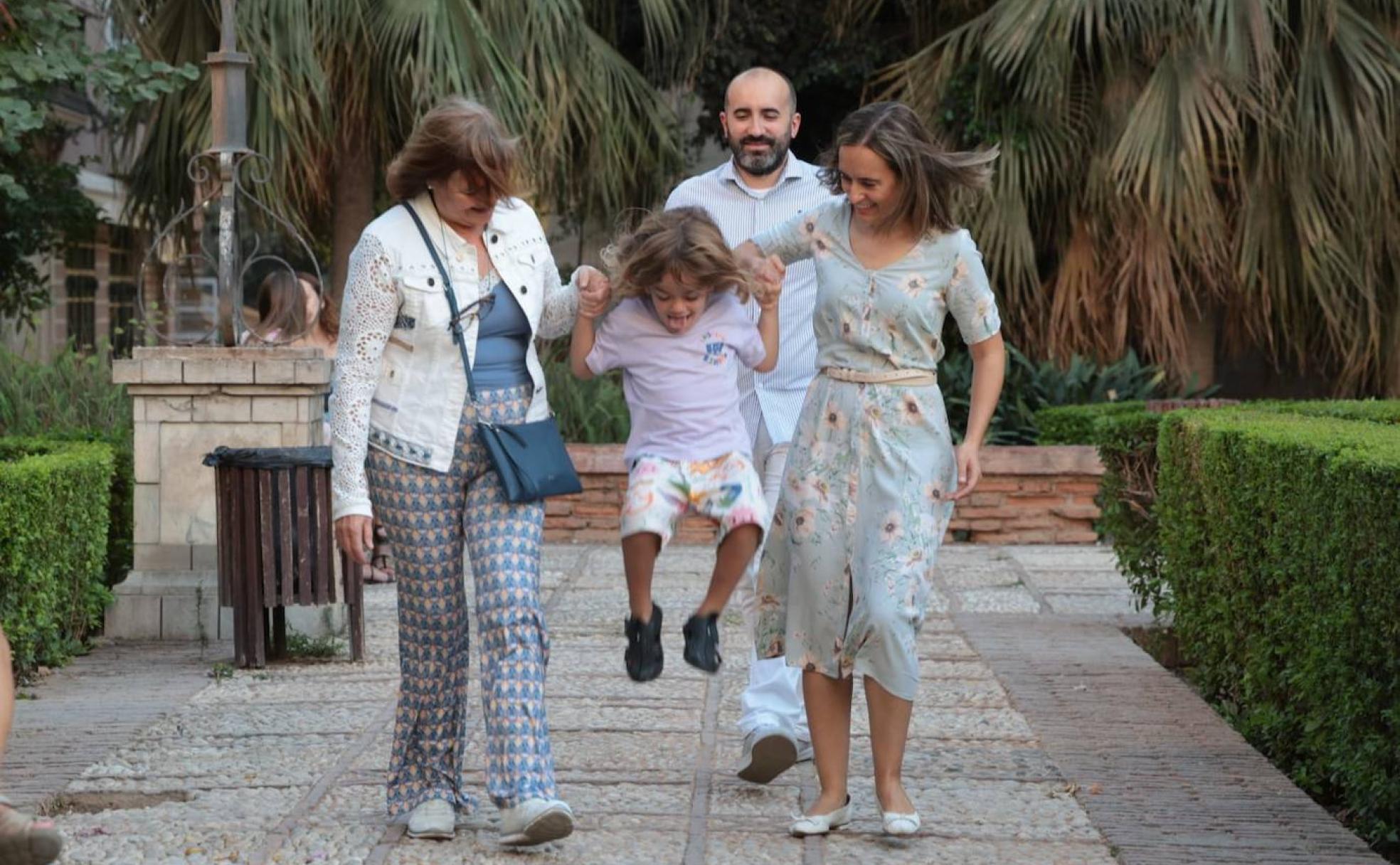El pequeño Leo salta en los jardines del patio de los Naranjos, uno de sus lugares favoritos para jugar, junto a su abuela y su madre Mercedes y con su padre David. 