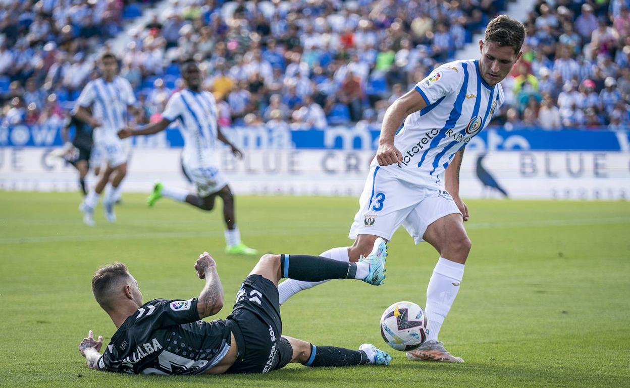 El jugador del Málaga, Fran Villalba, intenta mantener el balón desde el suelo ante el defensa del Leganés Jorge Sáenz.