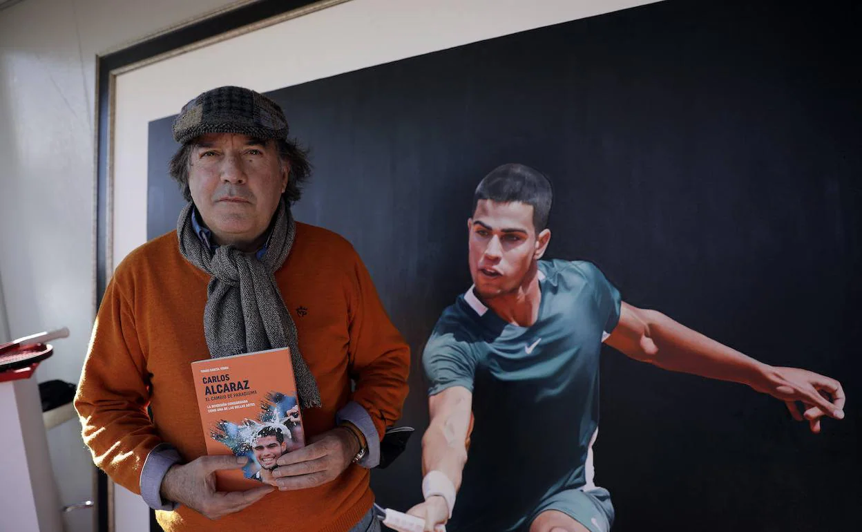 El escritor Tomás García Yebra, ayer en la Fanzone de los exteriores del Martín Carpena, con su libro y una imagen al fondo de Alcaraz. 