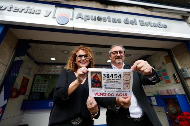 Los propietarios de la administración 'Lotería del Rosario' de Zaragoza posan con una réplica del número 38454, uno de los quintos premios