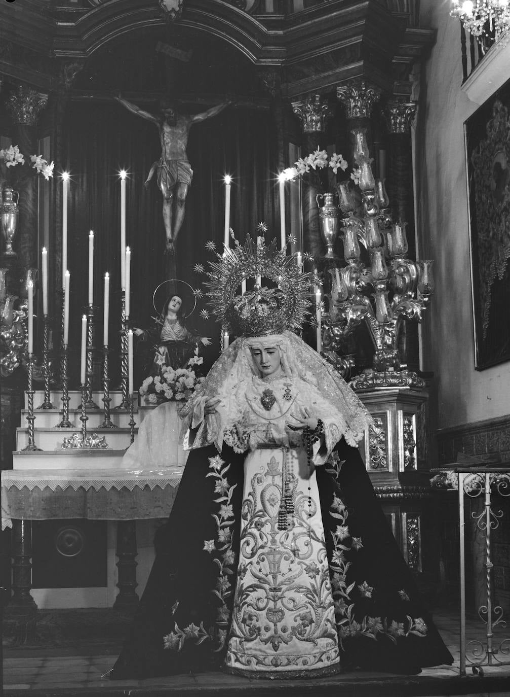 Curiosa fotografía de todas las imágenes titulares de la Cofradía del Amor en la capilla Castrense, ya desaparecida, ante el santuario de la Victoria, en la que tuvo su sede desde 1949 a 1972. Puede estar captada en los años sesenta. En los extremos del altar se han colocado parte de los arbotantes del gigantesco trono de la Virgen que realizó Pedro Pérez Hidalgo.