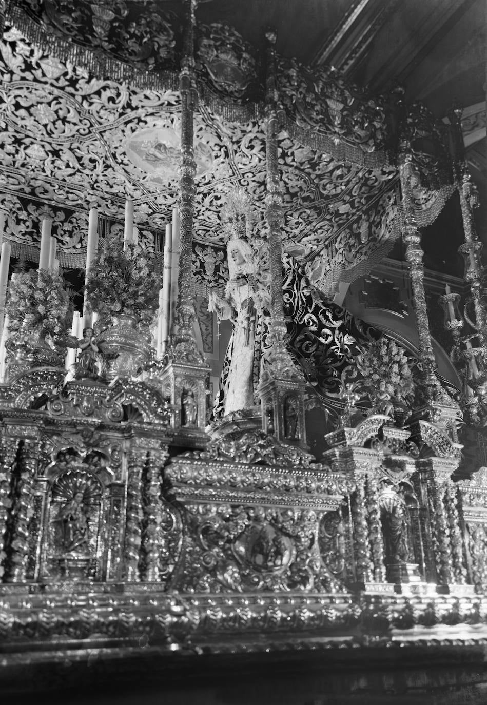 Hasta la construcción de la casa hermandad, el trono de la Virgen de los Dolores Coronada salió desde la actual capilla anexa a la parroquia de San Pedro en la que los titulares de la Expiración son venerados durante todo el año. El objetivo de Arenas capta la grandiosidad y calidad del palio, realizado por el taller sevillano de Esperanza Elena Caro a mediados de los años cincuenta.