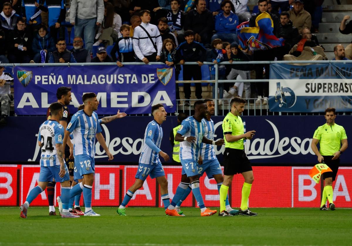 Jugadores del Málaga tras el árbitro De la Fuente Ramos para reclamar una de sus decisiones en el partido contra el Levante en La Rosaleda.