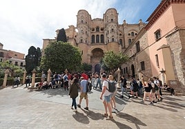 Turistas descansan en la plaza de los Naranjos, junto a la Catedral.