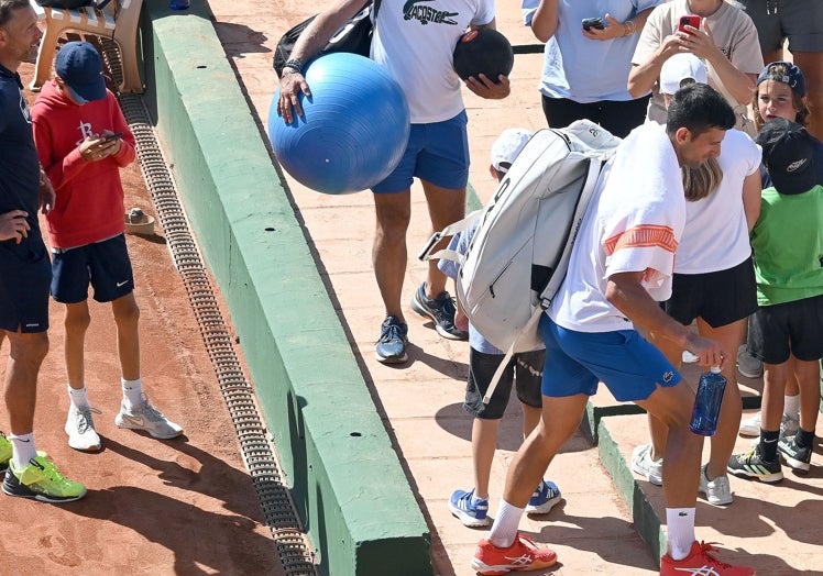 Novak Djokovic sube una grada para dirigirse a la pista de entrenamiento entre algo de público curioso.