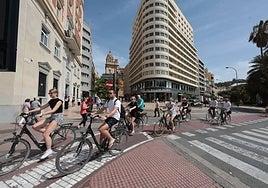 Turistas en bicicleta pasan por delante del AC Marriott Málaga Palacio.