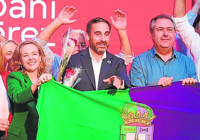 Dani Pérez, con la bandera de Málaga, entre Nadia Calviño y Juan Espadas.