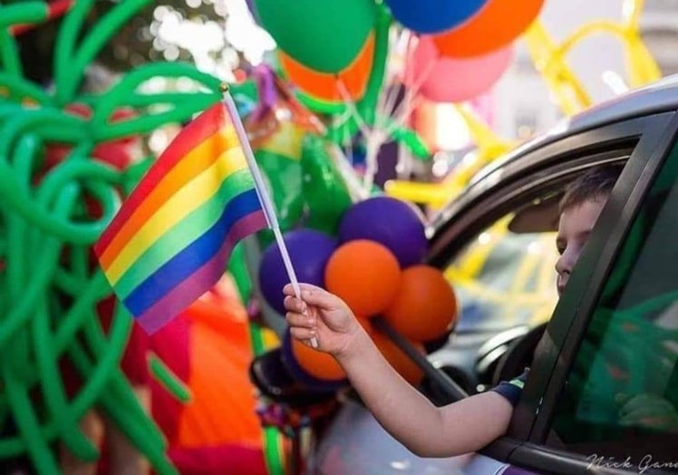 Un niño saca su banderín desde el coche.