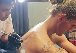 Un tatuador trabaja sobre la espalda de Osetkowski.