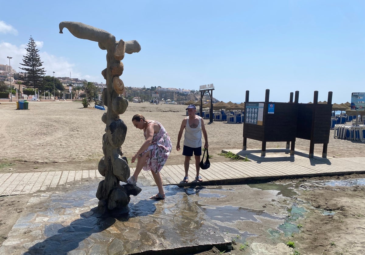 Bañistas usando un lavapiés en la playa rinconera de La Cala del Moral.