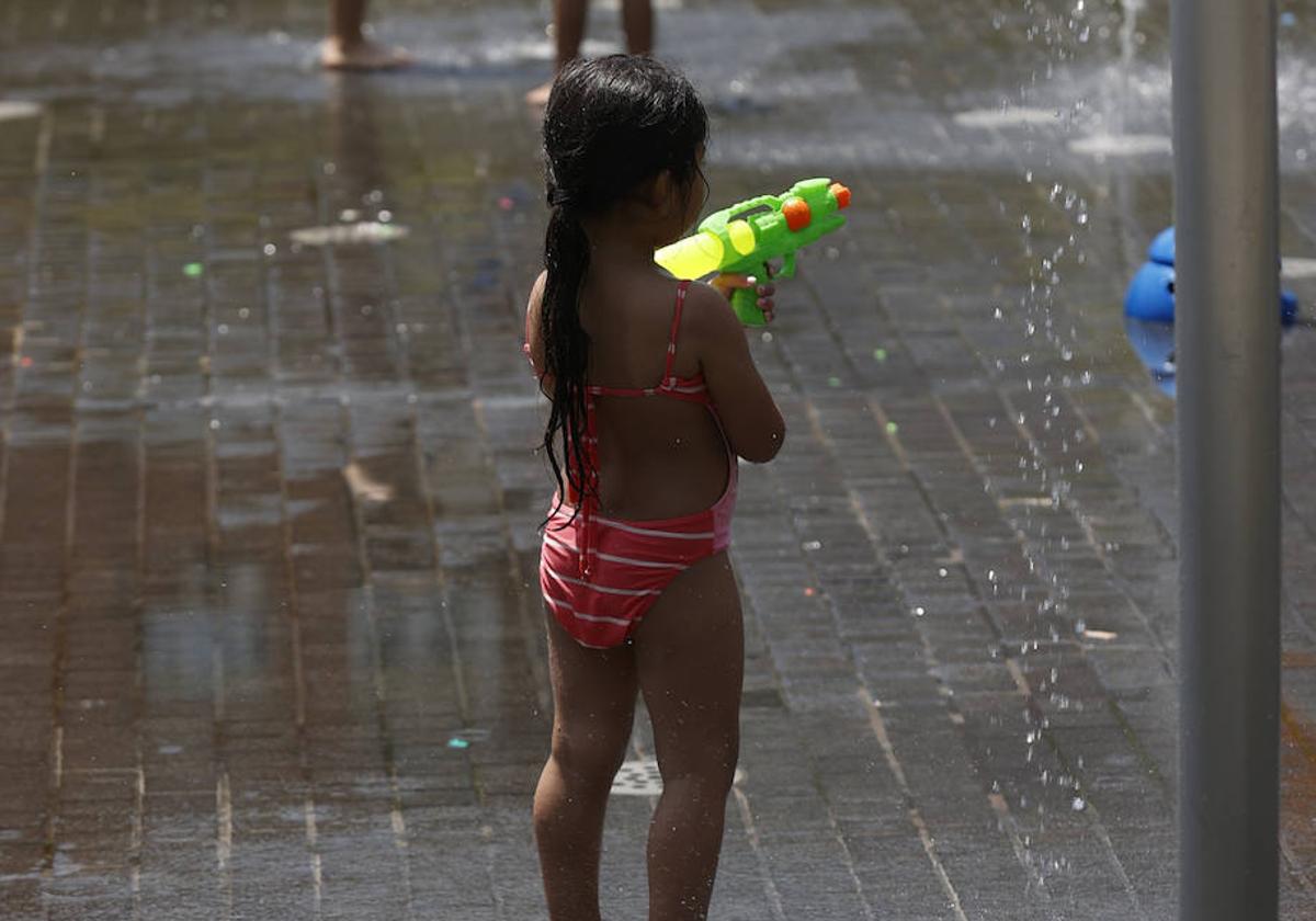 Una niña juega en una fuente de chorros en Madrid, este lunes.