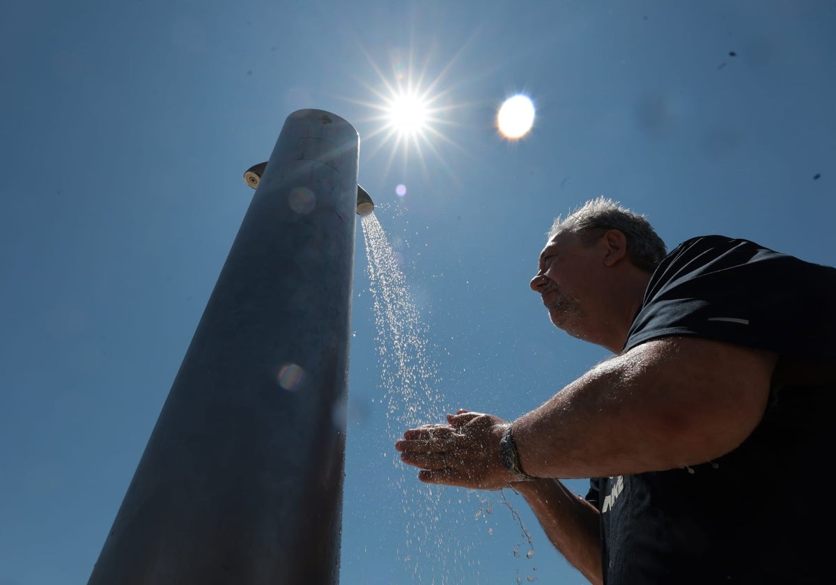 Un hombre se refresca en una de las duchas de la playa en Málaga.