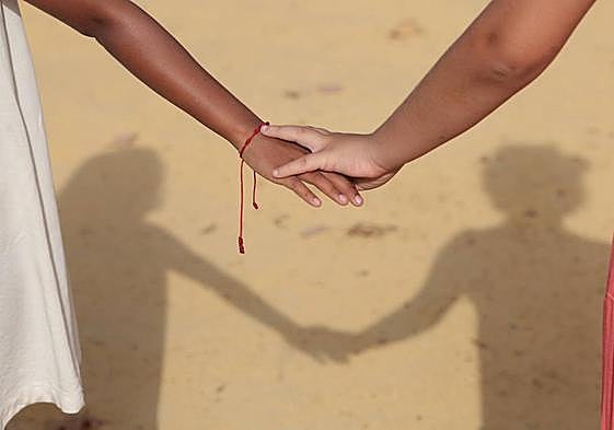 Las dos niñas en acogida en casa de María y Ricardo pasean cogidas de la mano por el pueblo malagueño en el que residen.