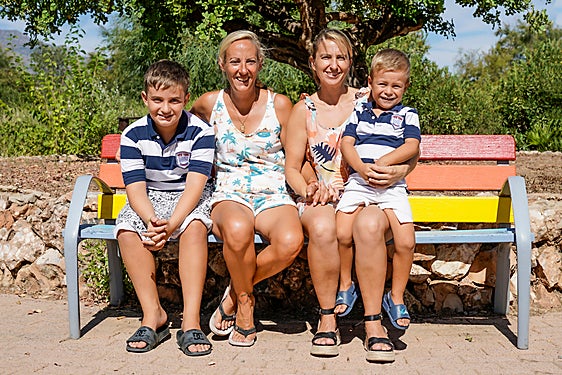 Vanessa bromea con su hijo pequeño mientras Miriam y su hijo mayor los observan sonrientes.