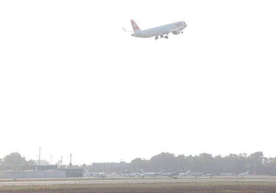 Un avión comercial despega sobre la zona de estacionamiento de aviones ejecutivos en el Aeropuerto de Málaga.