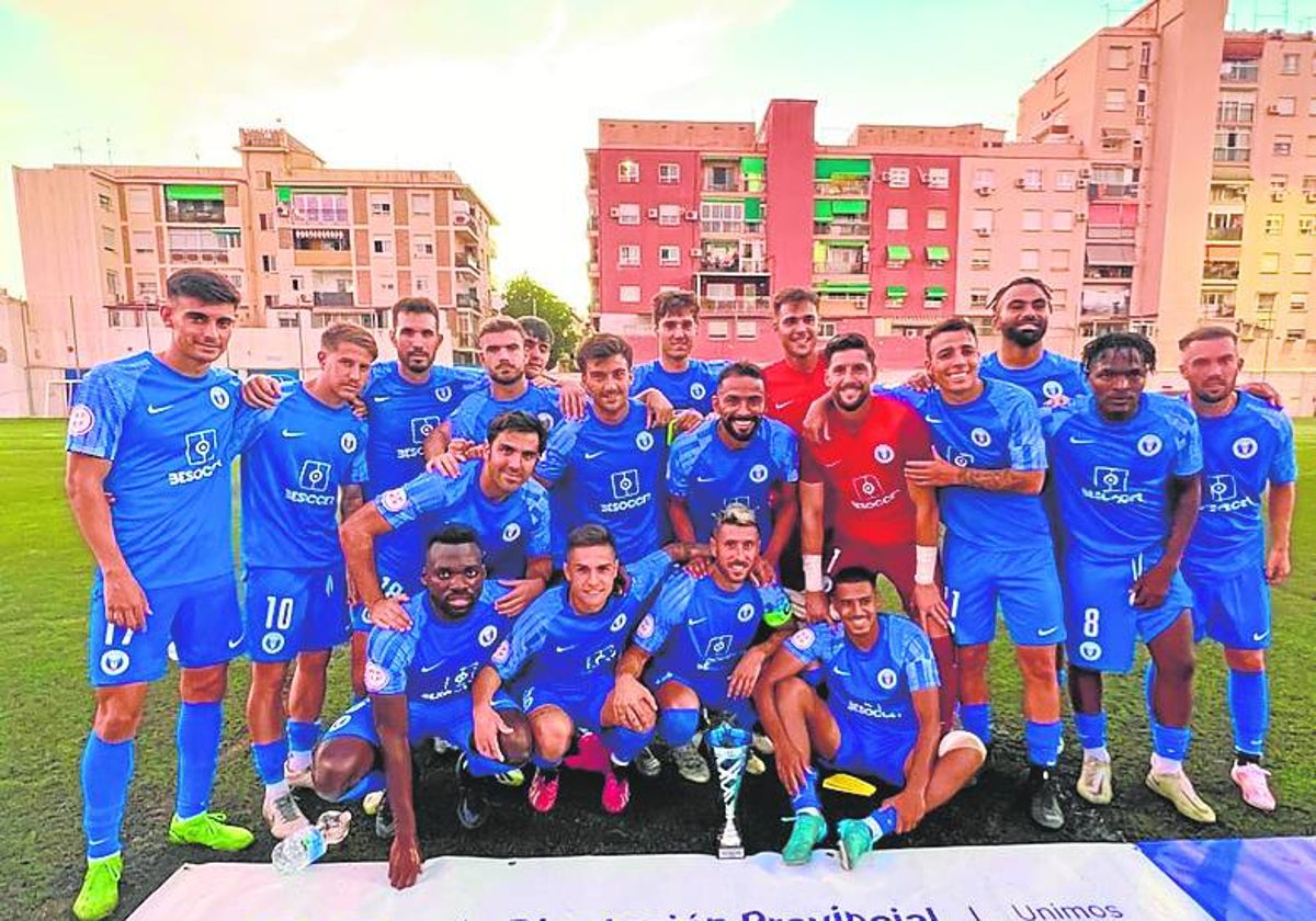 La plantilla de El Palo posa tras un trofeo de pretemporada en casa.