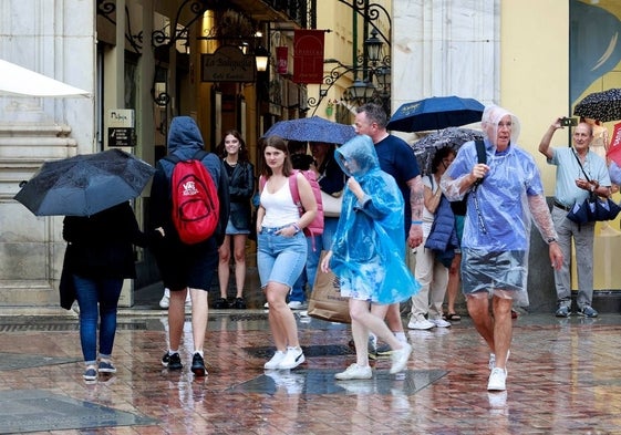 Turistas bajo un chaparrón en el Centro de Málaga.