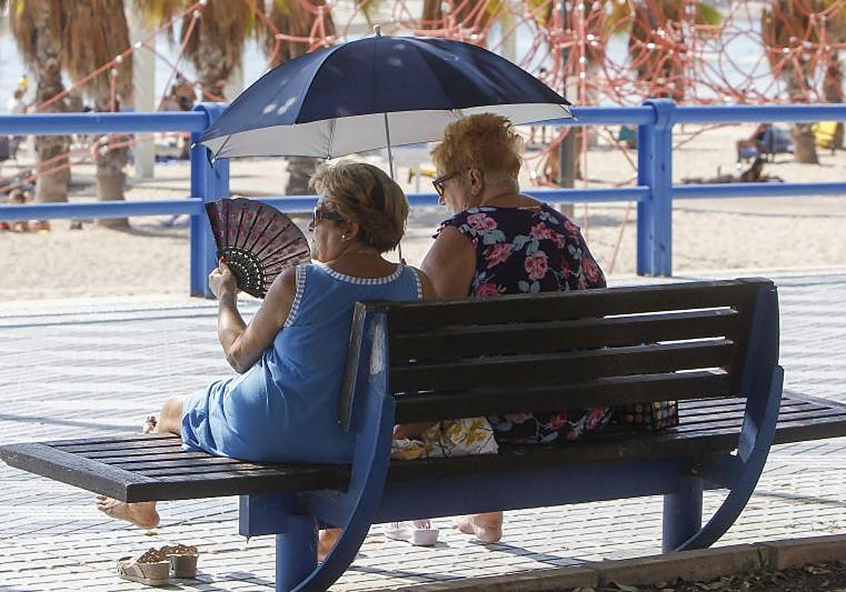 Dos mujeres se protegen del sol en un paseo marítimo ante las altas temperaturas en este arranque del otoño.
