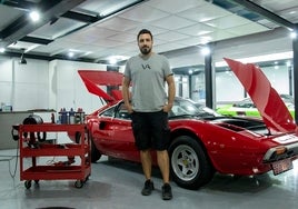 Álvaro González junto a un Ferrari 308, una de los tantísimas joyas que pasan por su local a diario.