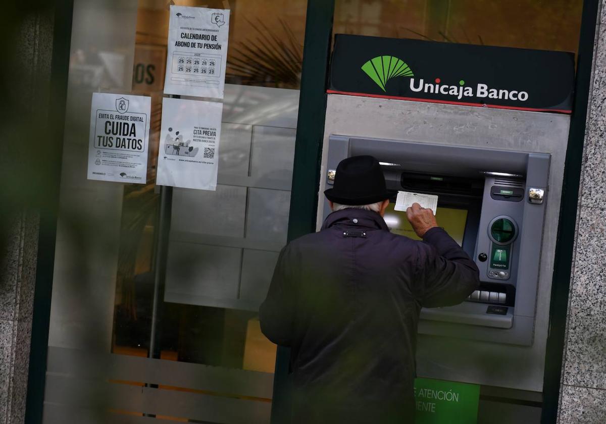 Un hombre en un cajero automático de una sucursal de Unicaja Banco.