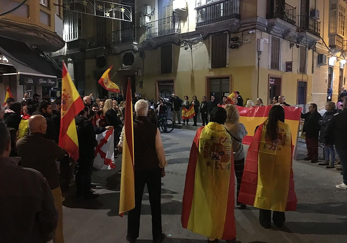 Grupo de personas con banderas de España a las puertas de la sede del PSOE en Málaga.