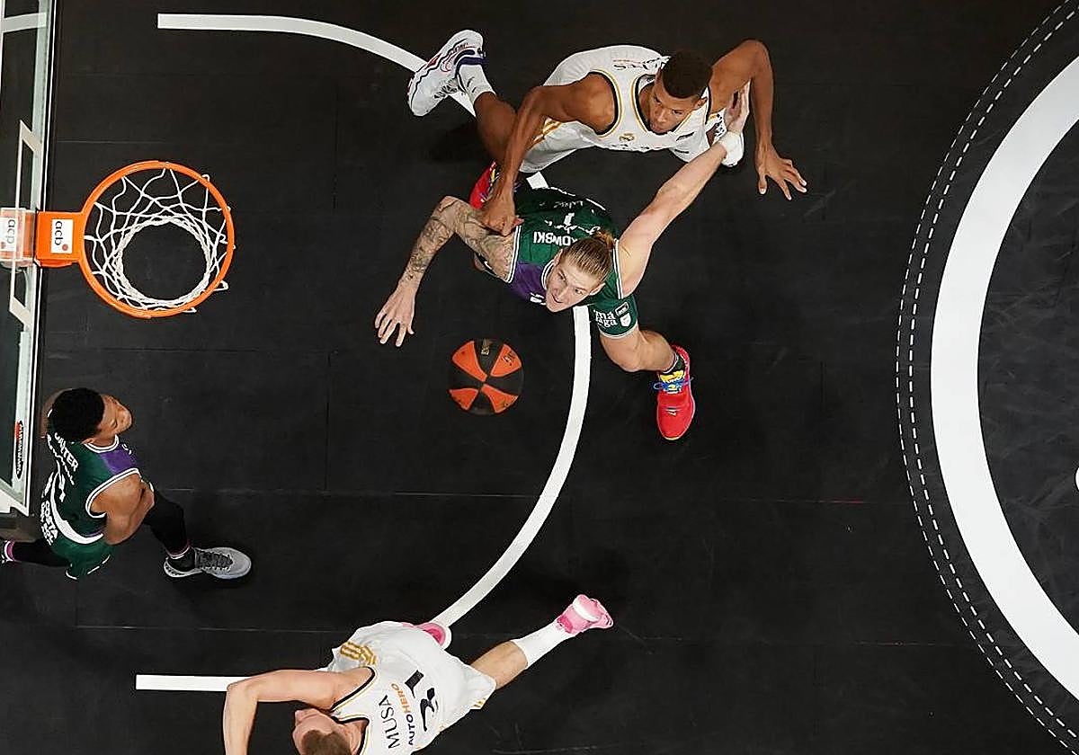 Osetkowski y Tavares observan el balón para tratar de hacerse con un rebote.