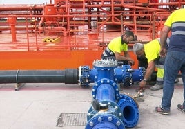 Operarios en el puerto de Bermeo durante un trasvase de agua en barco.