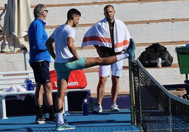 El preparador físico de Djokovic, Marco Panichi, Novak Djokovic y Daniel Evans, este jueves en una de las pistas de Puente Romano.