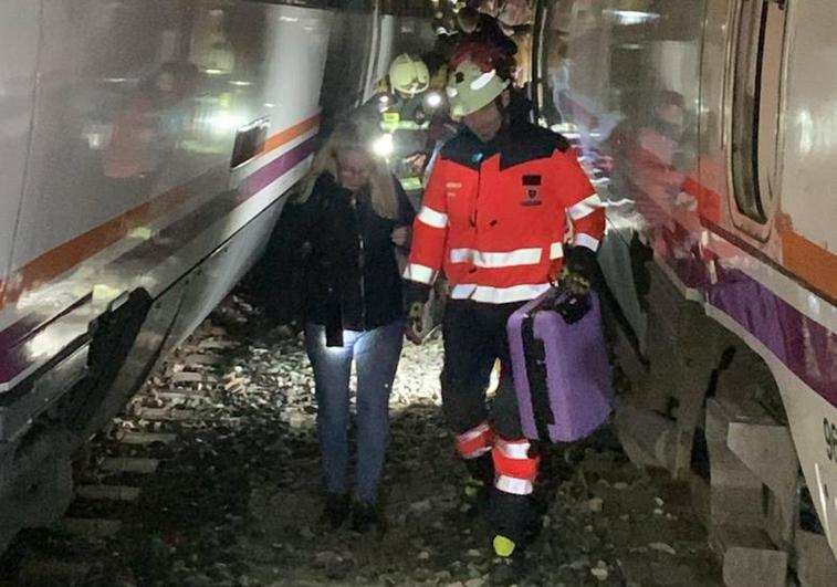 Pasajeros ayudados por bomberos tras salir del tren.
