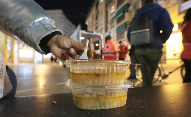 Una persona con los 'tupper' de comida que reparten los voluntarios. 