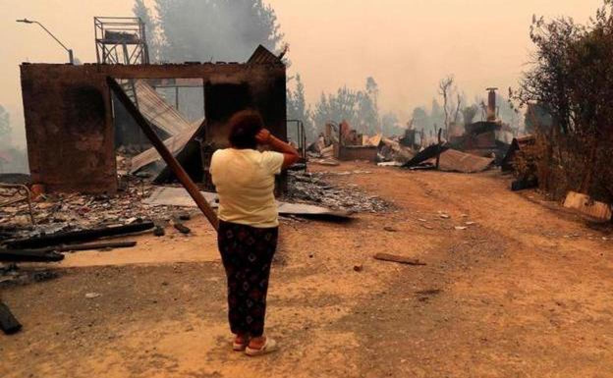 Una mujer observa una casa destruida durante un incendio en la localidad de Santa Juana