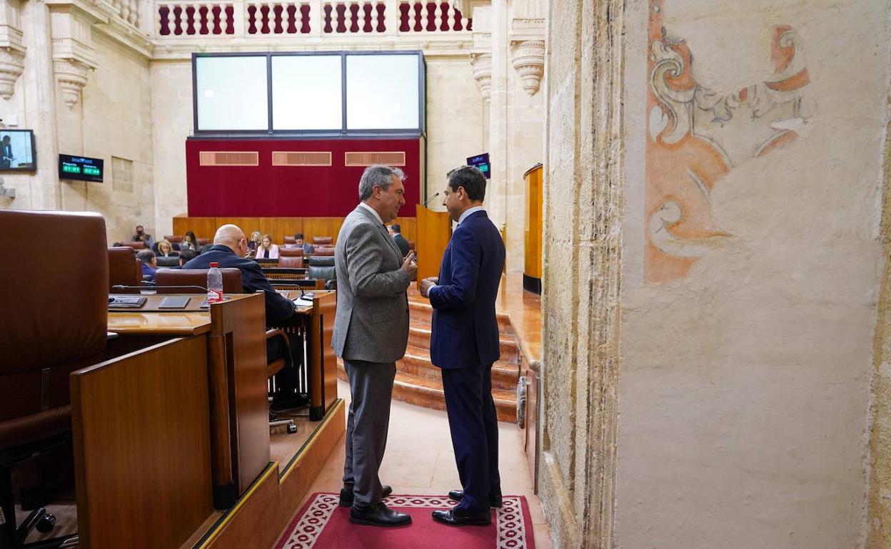 Juanma Moreno y Juan Espadas conversan en el Parlamento de Andalucía antes de comenzar la sesión plenaria. 