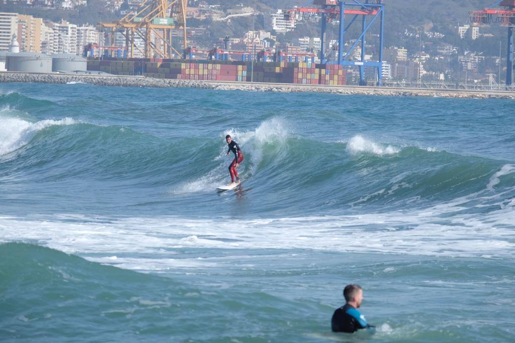 Tablas y ganas de coger olas en la playa de Huelin, este domingo. Surfistas aprovechan el viento de levante y la olas del temporal para meterse en el agua en distintos puntos de Málaga