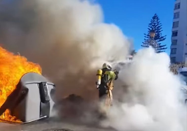 Un bombero de Mijas trabaja para sofocar las llamas en un contenedor.