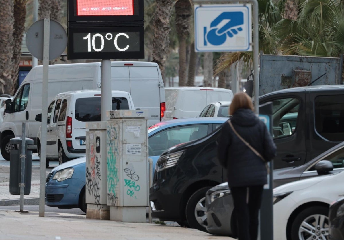 Una persona camina bajo un termómetro que marca 10 grados en Málaga.