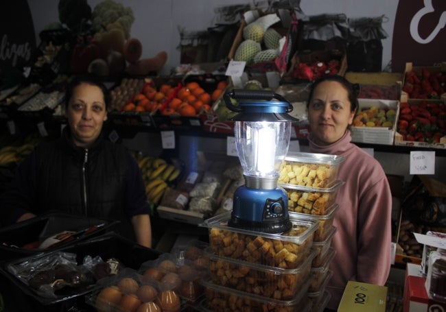 Las hermanas Raquel y Ángela Núñez, en su frutería, con un candil a pilas.