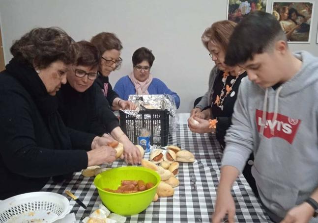 Voluntarias preparan bocadillos con chorizo para su posterior reparto.