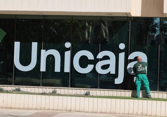 Un trabajador limpia los cristales de la sede de Unicaja en la Avenida de Andalucía.