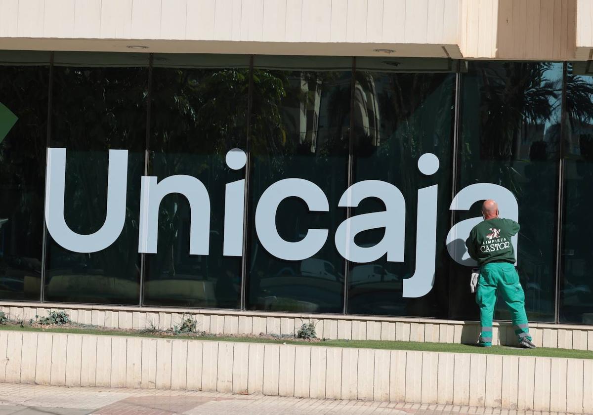 Un trabajador limpia los cristales de la sede de Unicaja en la Avenida de Andalucía.