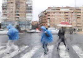 Peatones cruzando bajo la lluvia este sábado en la zona de Cuarteles y Correos.