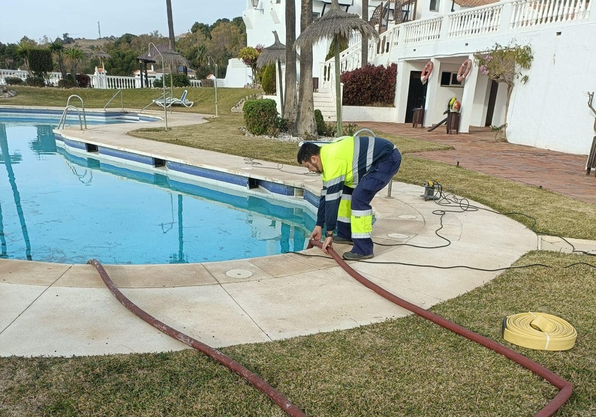 Un operario municipal retira el agua de la piscina de una comunidad de vecinos, que decidió donarla al Ayuntamiento de Benalmádena ante la actual situación de sequía.