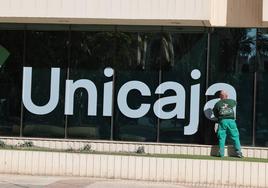 Un trabajador limpia los cristales de la sede de Unicaja en Málaga.