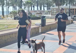 Una joven corre con su perro por la playa de La Carihuela de Torremolinos.