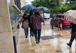 Un grupo de personas camina bajo la lluvia en el Centro de Málaga, esta mañana.