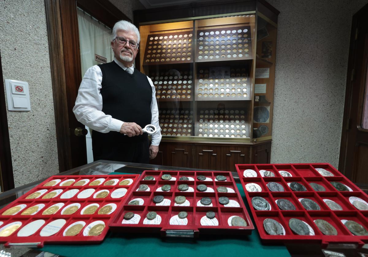Gonzalo González ante tres bandejas de monedas españolas, de oro, fenicias y romanas.
