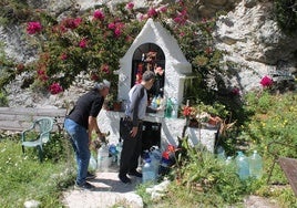 Dos devotos dejan sus recipientes con agua junto a la capilla.